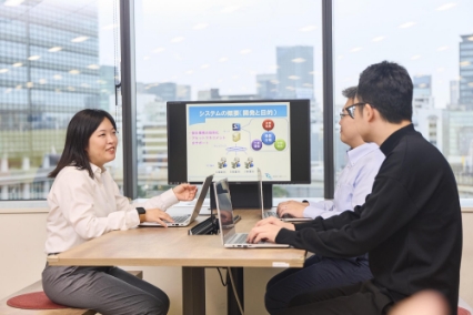 オフィスでモニターを見ながら打ち合わせする社員